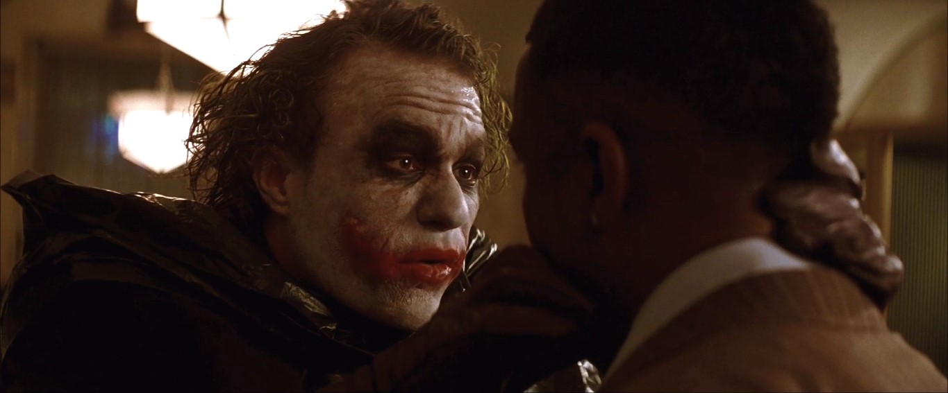 Хочешь знать, откуда эти шрамы? Мой папаша был алкаш и изверг, и однажды он взбесился больше обычного. Мамочка схватила кухонный нож, чтобы себя защитить, но папочке это не понравилось! И вот у меня на глазах он её зарезал, хохотал как сумасшедший. Потом повернулся и говорит: «Чего ты такой серьёзный, сынок?» Он шёл на меня с ножом... «Чего ты такой серьёзный, сынок?!» Он вставил мне лезвие в рот: «Давай-ка мы тебе нарисуем улыбку!» И... «Чего ты такой серьёзный?»